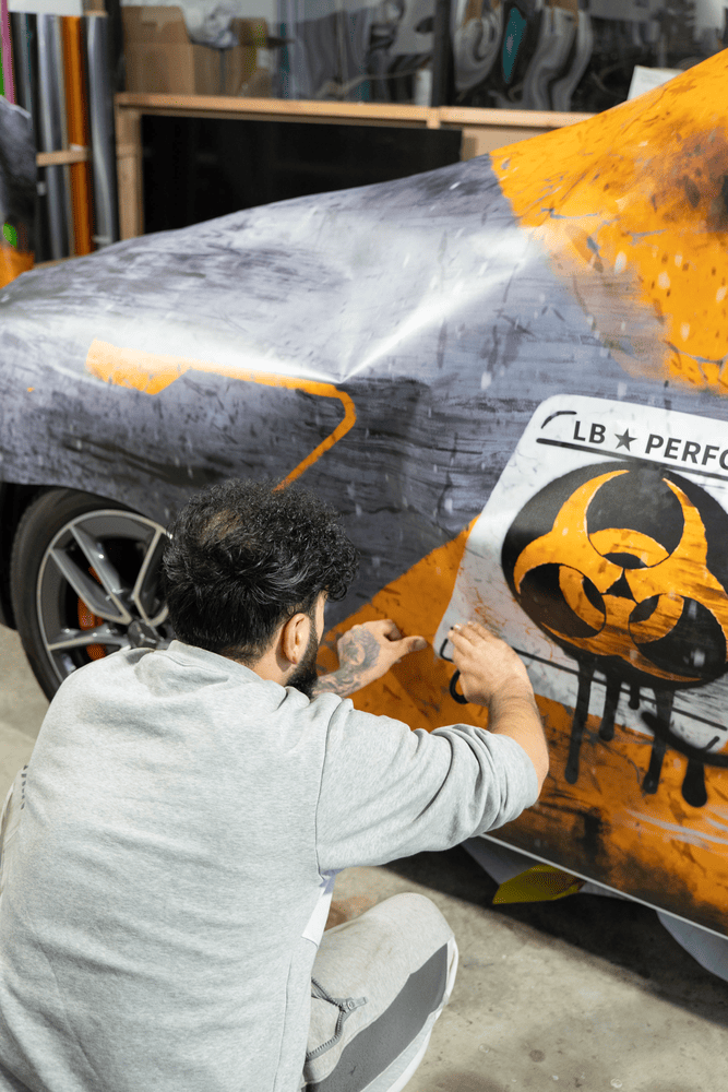 „Mitarbeiter von Autofolierung Frankfurt beim Anbringen einer farbigen Lackschutzfolierung auf einem Fahrzeug – professionelle Autofolierung in Frankfurt